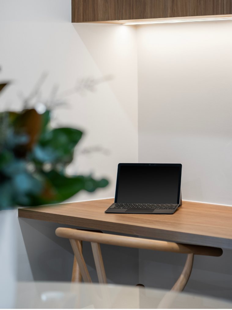 Built-in timber desk nook with a laptop and wishbone chair, accessible from the kitchen — 8 Bishop