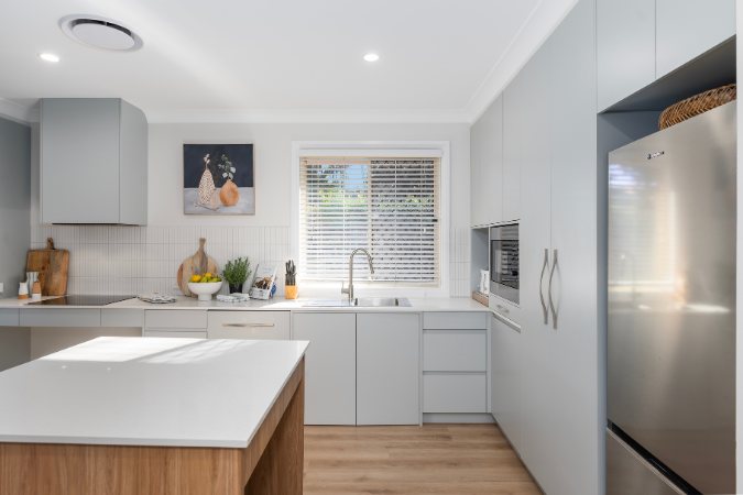 Grey kitchen cabinetry run with an integrated stainless fridge and built-in oven — 8 Bishop