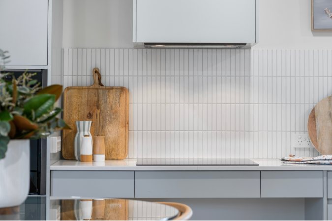 Cooktop with a tiled splashback, rangehood and timber chopping boards — 8 Bishop