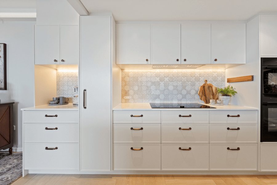 Full kitchen wall run with white cabinetry, mosaic tile splashback and integrated ovens — Kangaroo Point / Tess