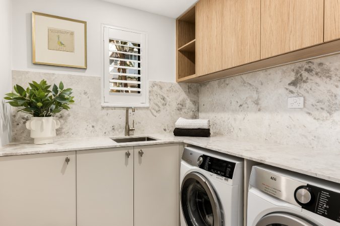 Laundry with a marble splashback, open timber shelving and integrated washer and dryer — Kangaroo Point Villa 8