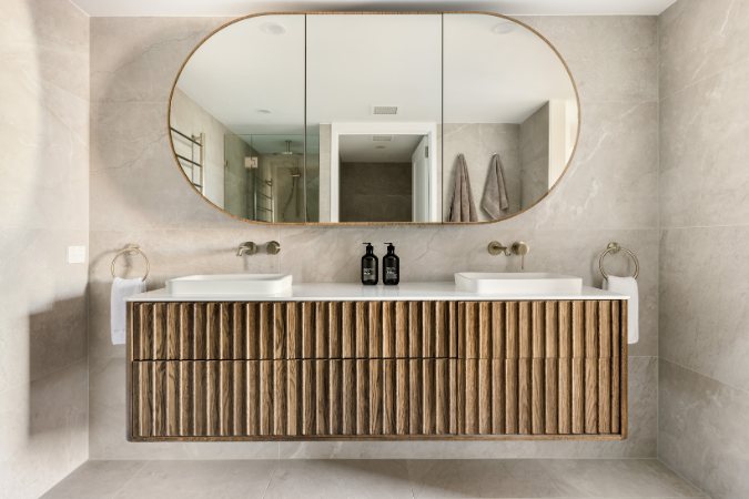 Dual-vanity bathroom with an oval mirror cabinet, fluted timber vanity and brass tapware — Kangaroo Point Villa 8