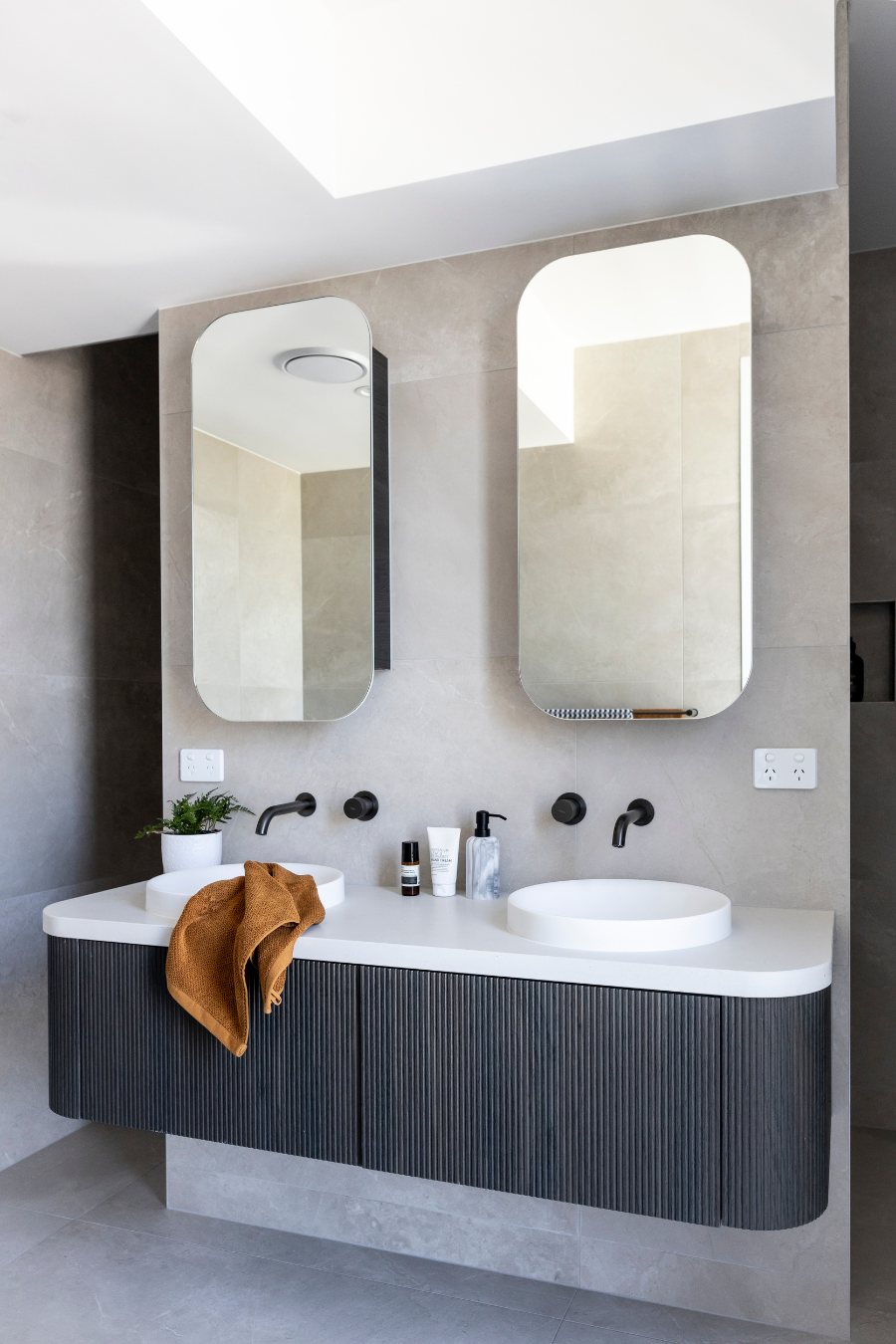 Ensuite with twin arched mirrors, round basins and a black fluted vanity — Monochrome Residence