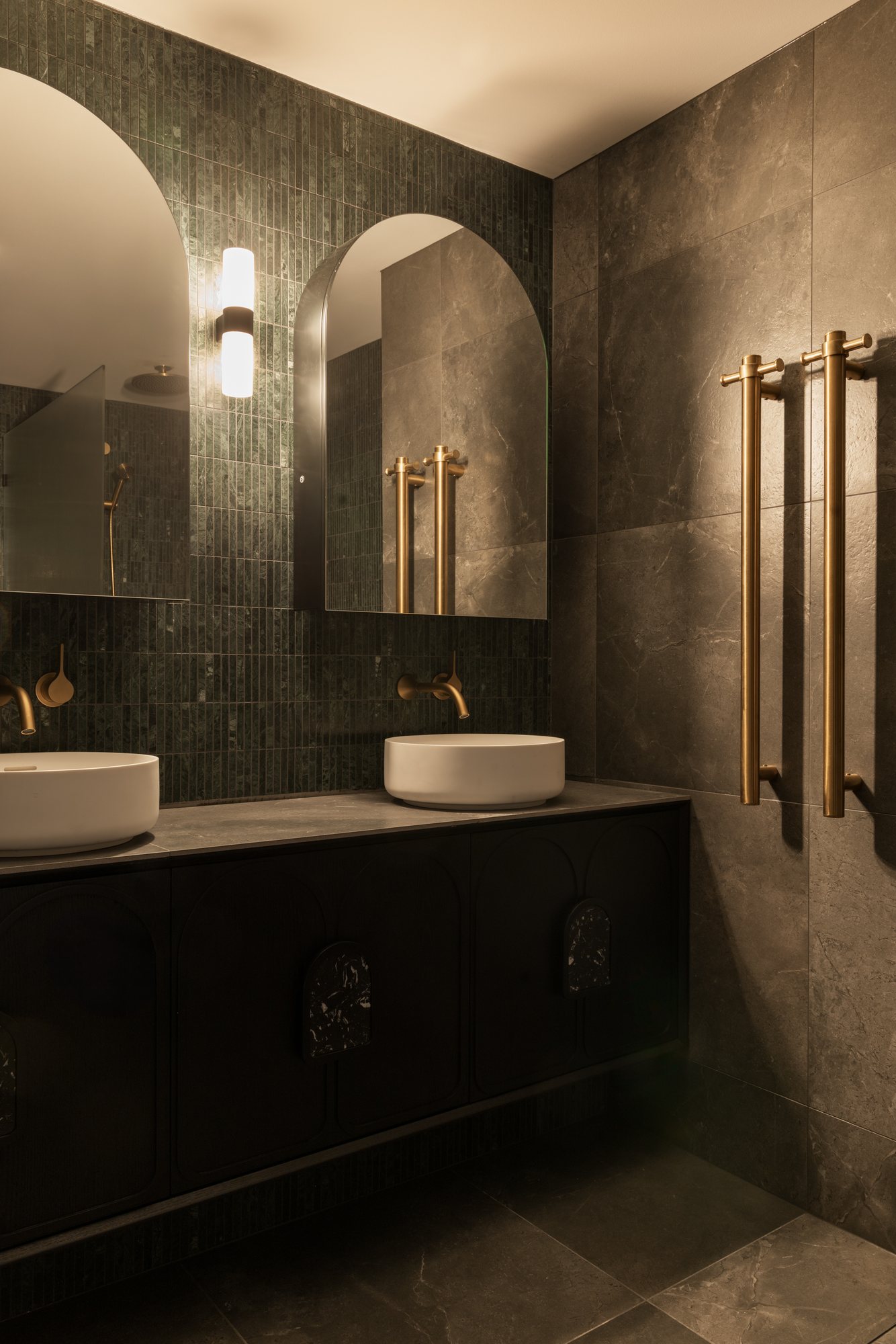 Ensuite with green tiled walls, twin arched mirrors and brass tapware and towel rails — Nundah