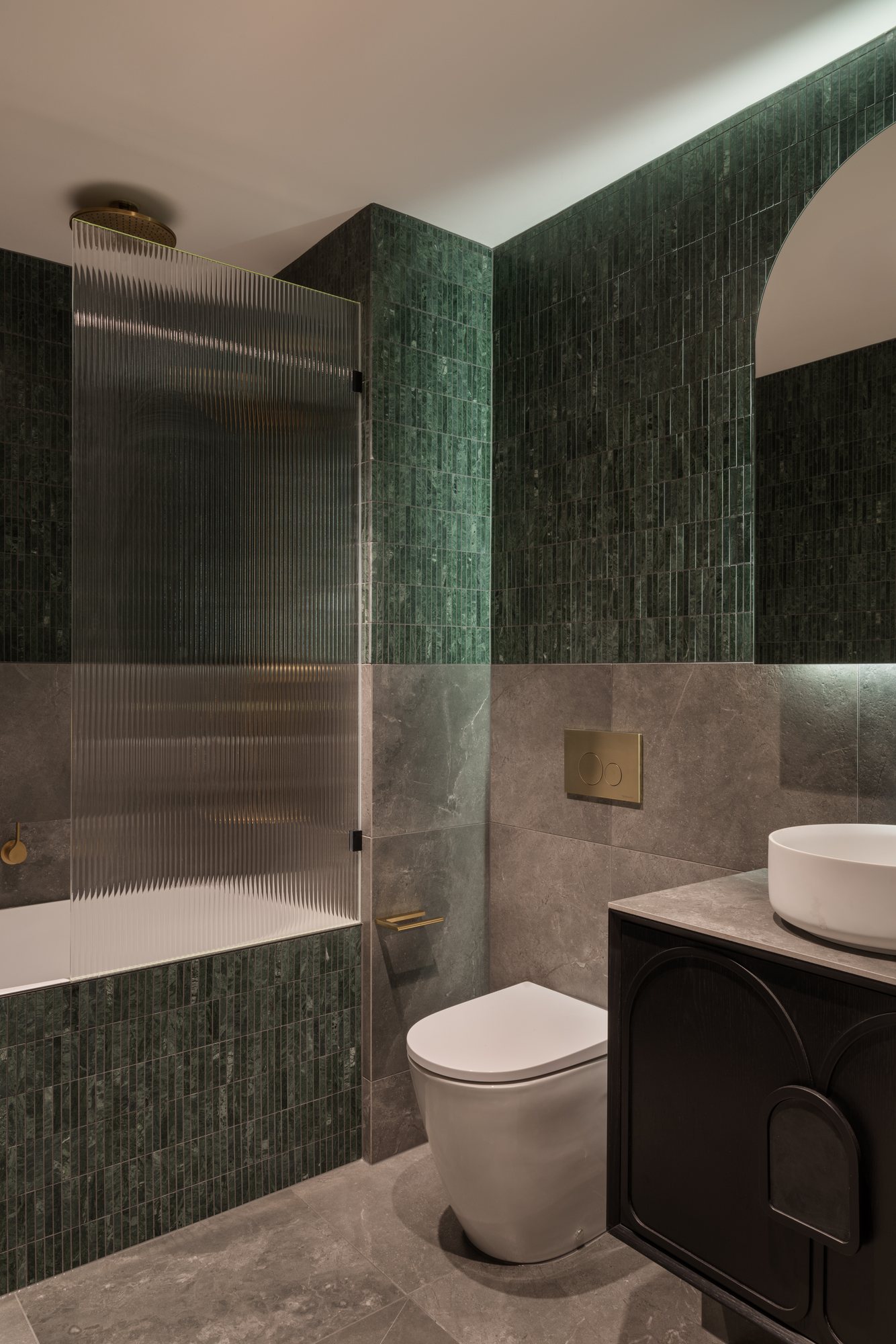 Bathroom with a fluted glass shower screen, green tiled walls and brass fittings — Nundah