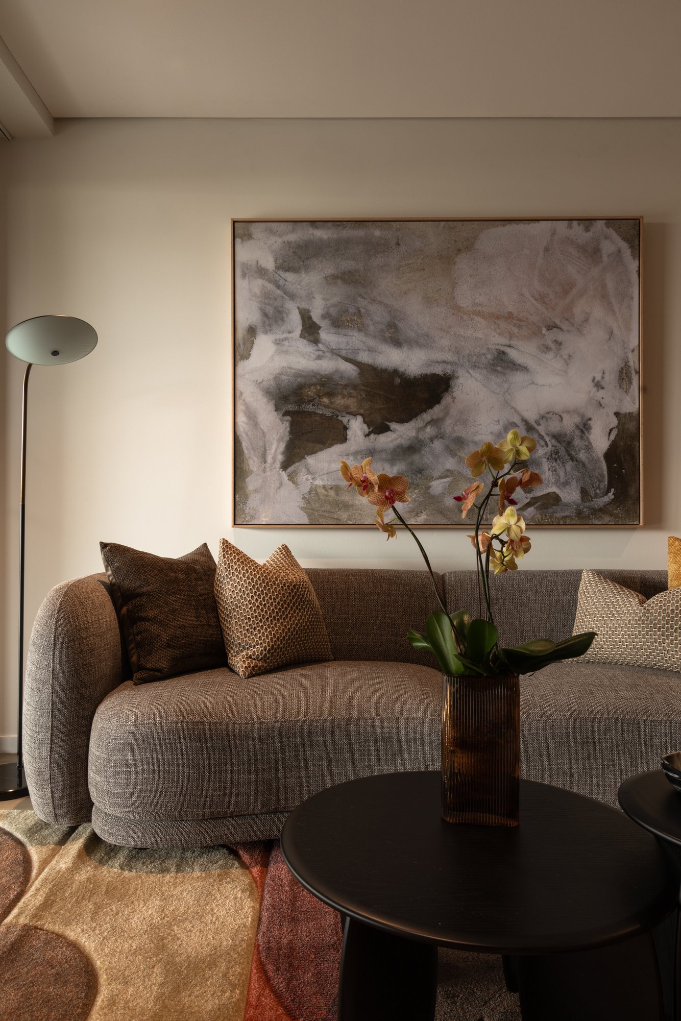 Living room sofa beneath an abstract artwork, with orchids on the coffee table — Nundah