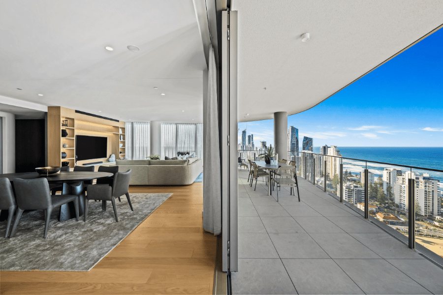 Living and dining opening onto a wraparound balcony with Gold Coast skyline and ocean views — Oceanside