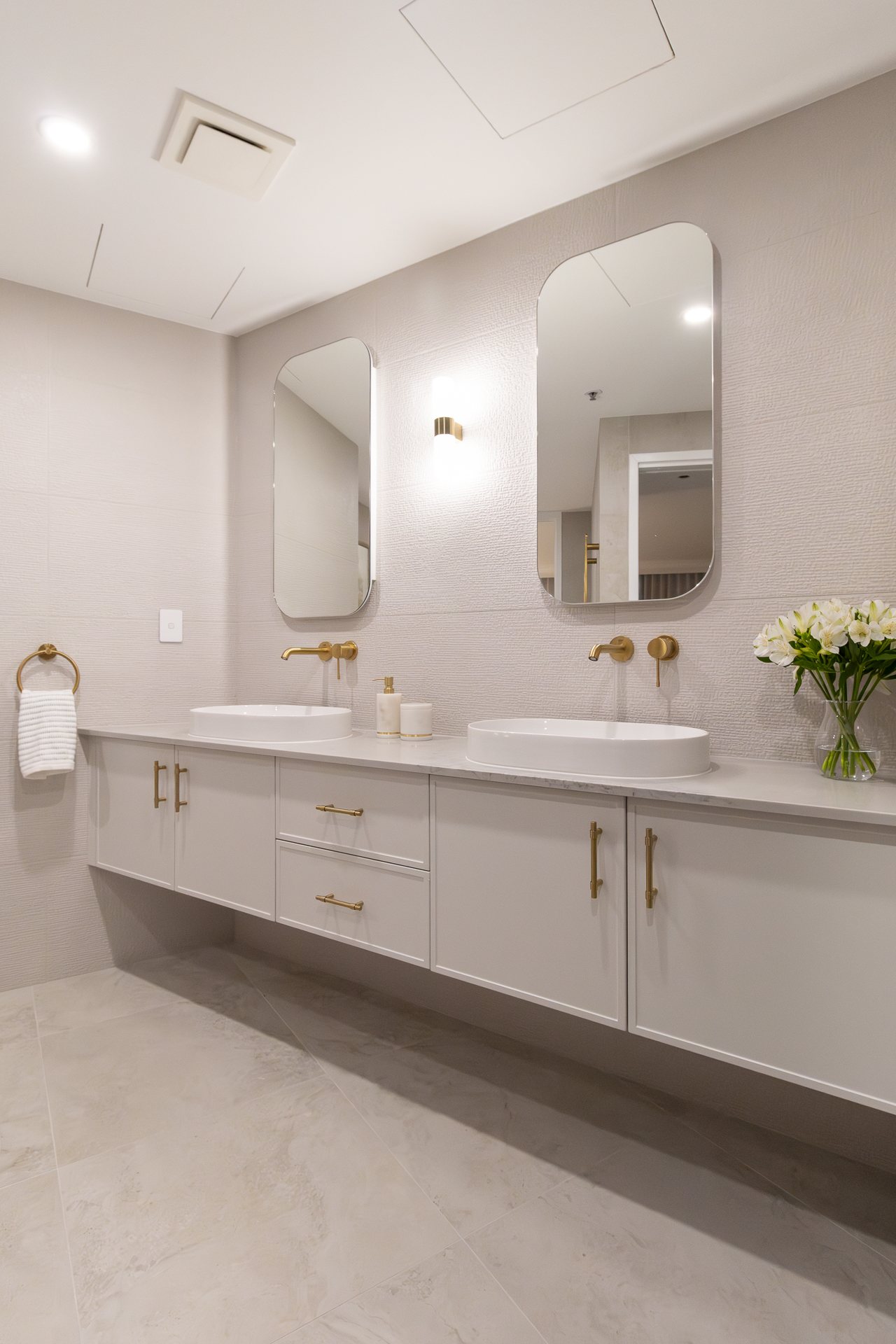 Dual-vanity bathroom with oval mirrors, vessel basins and brass tapware — Rivage
