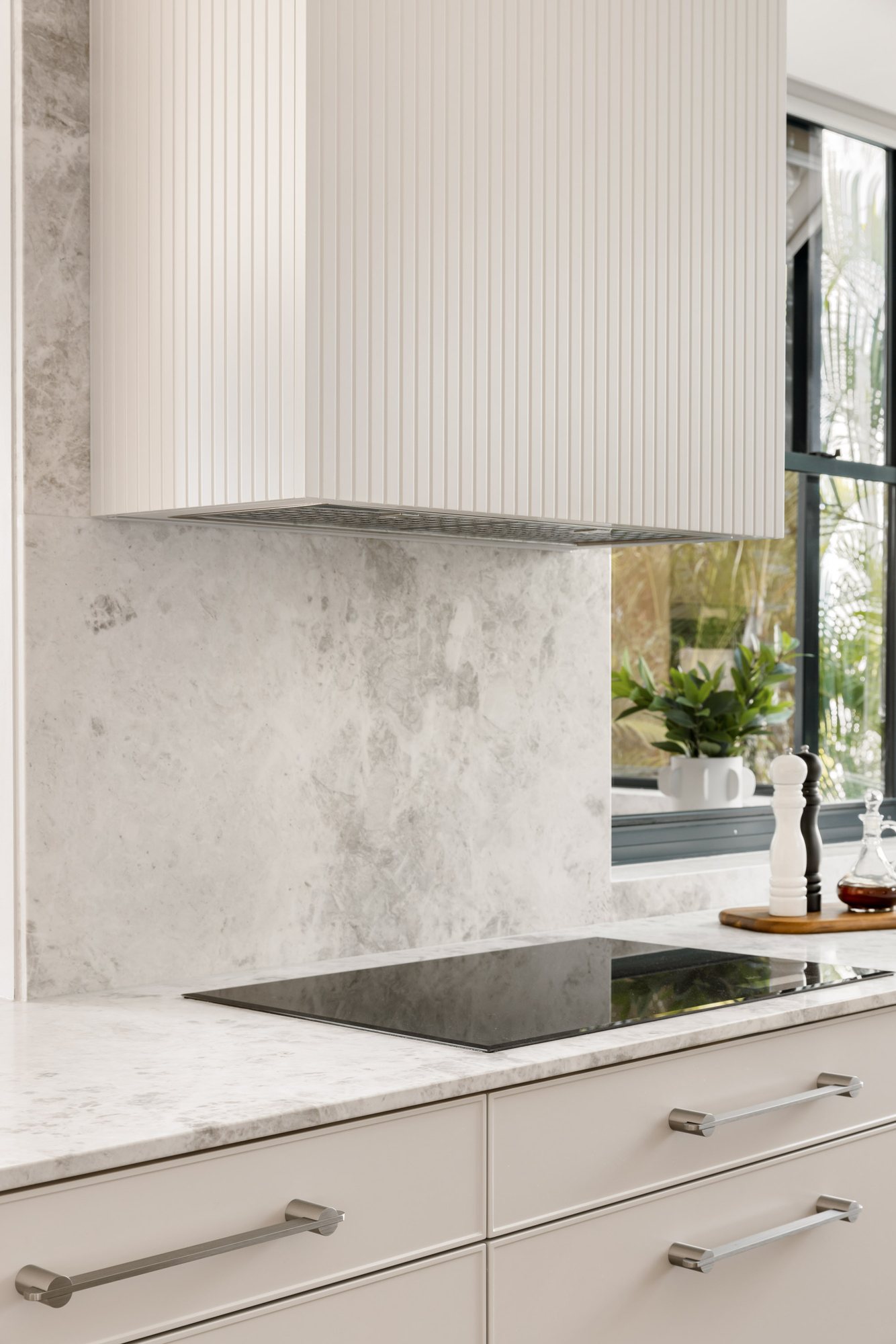 Fluted rangehood over a marble splashback and induction cooktop — Stradbroke Villa 8