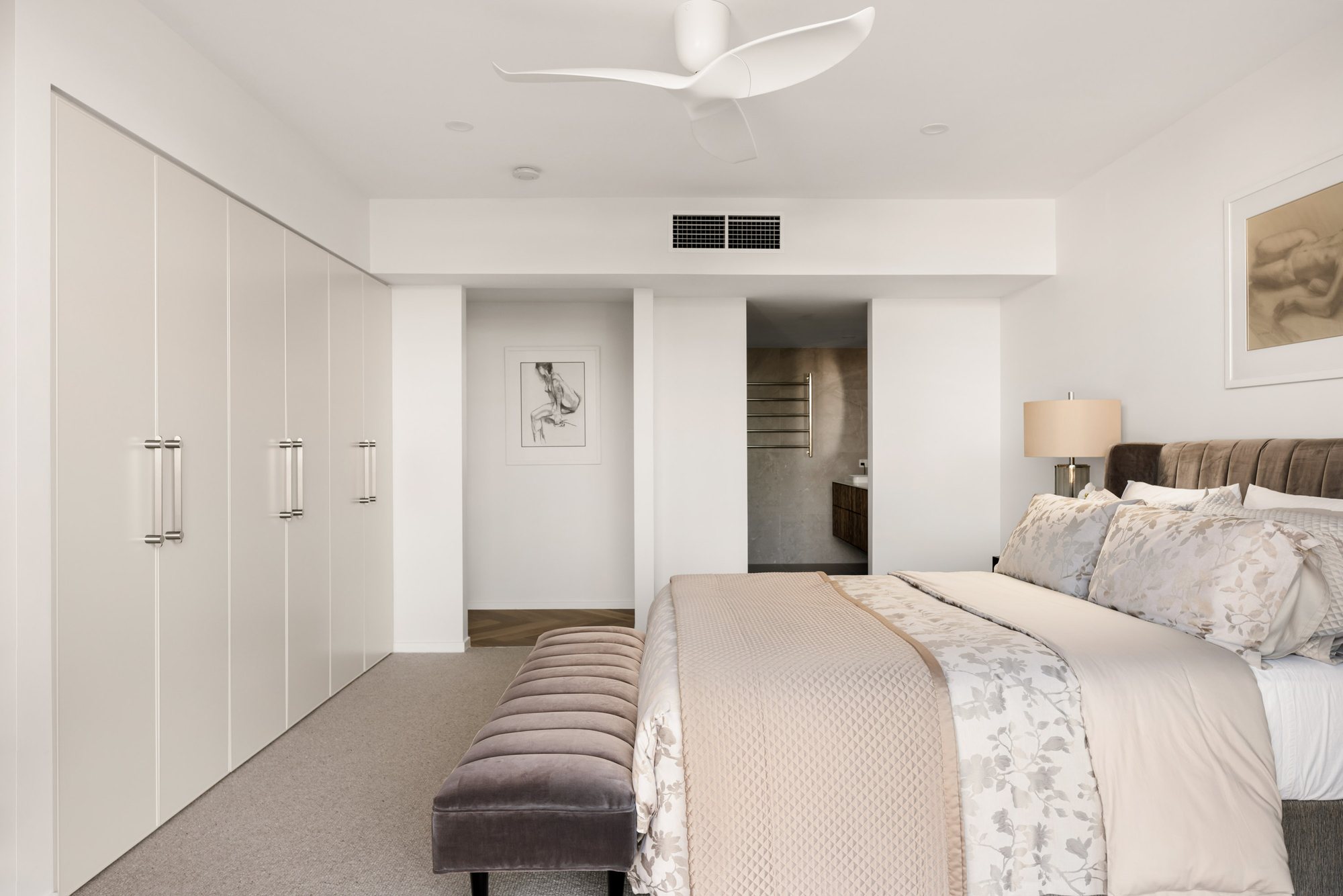 Bedroom with built-in wardrobes, floral bed linen and an ensuite glimpsed beyond — Stradbroke Villa 8