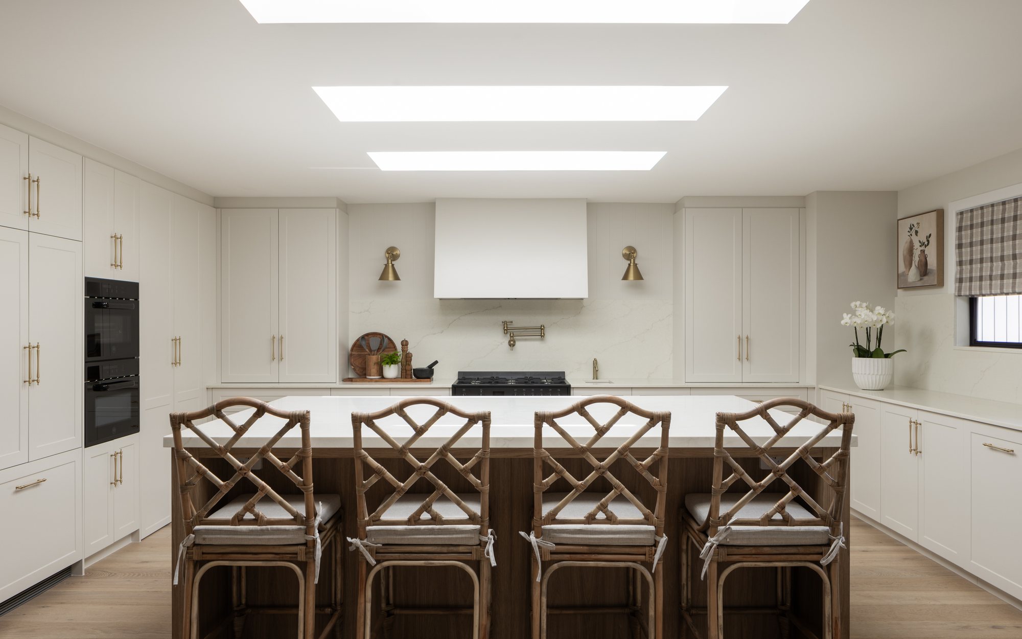 Kitchen with a large island, rattan counter stools and twin skylights — The Manor House