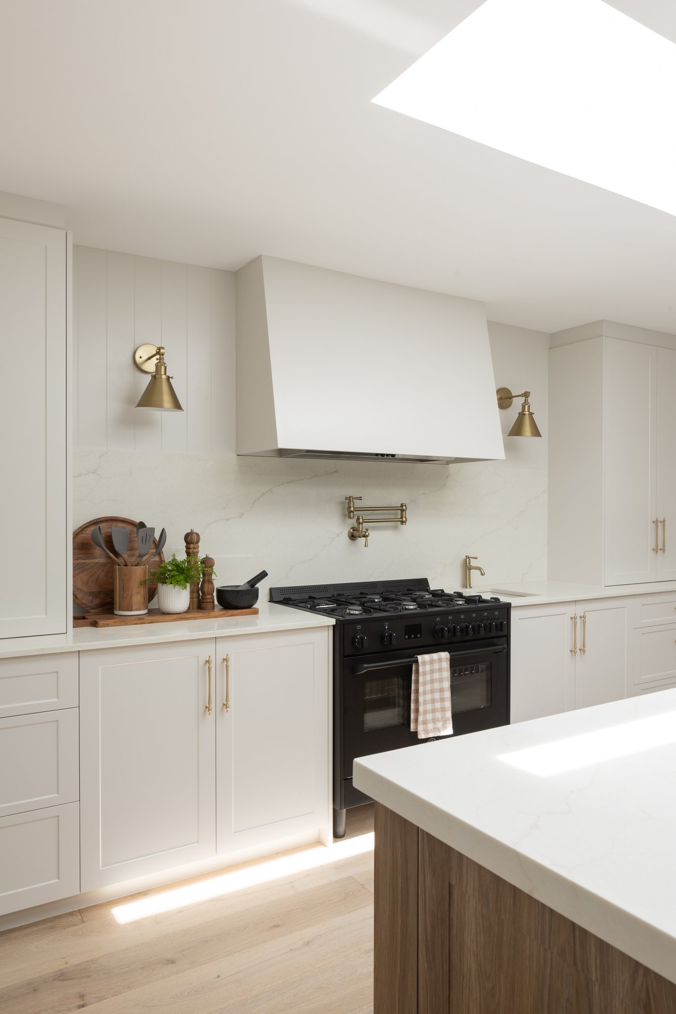 Freestanding range and rangehood with a marble splashback and brass pot-filler — The Manor House